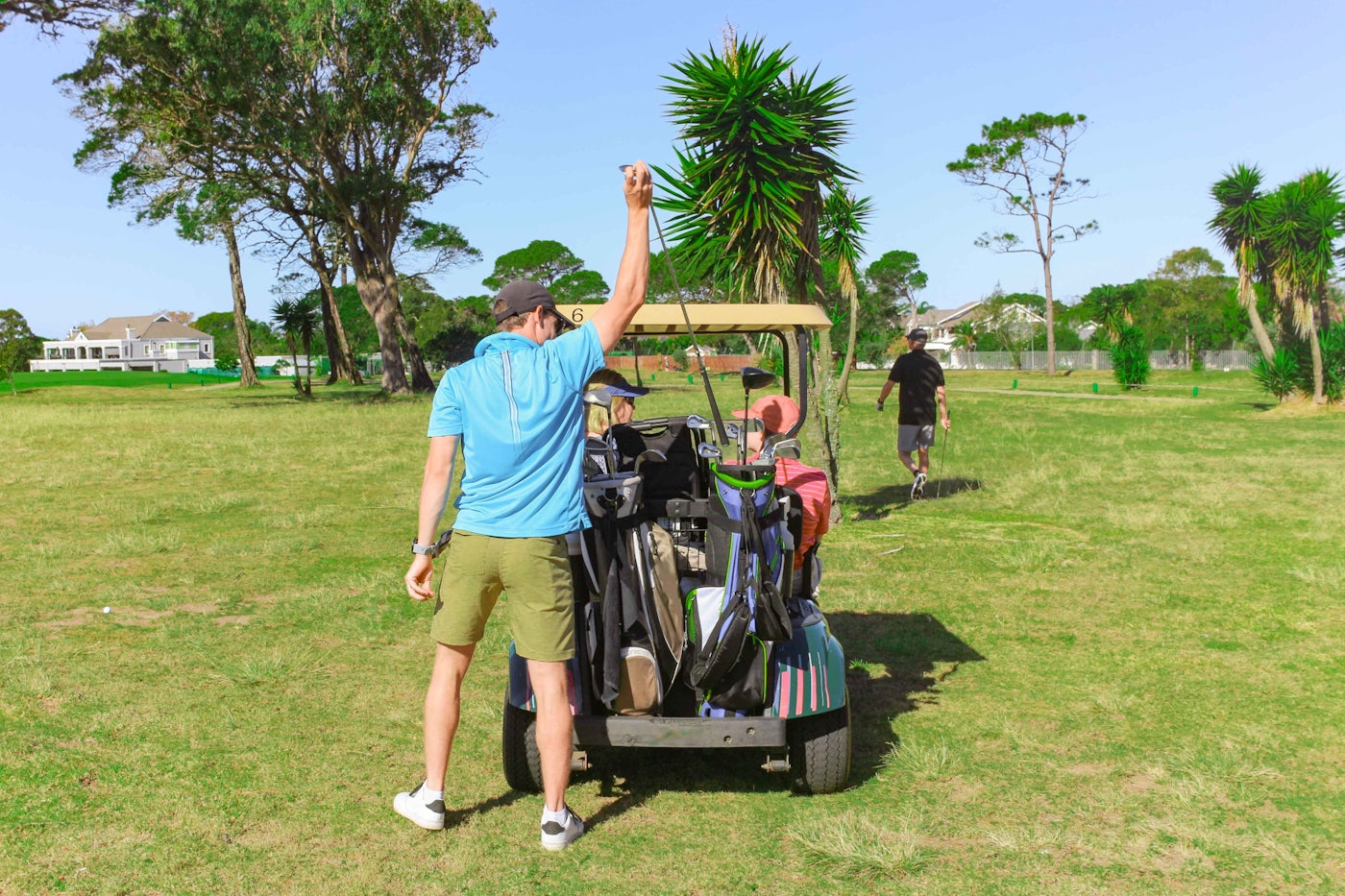 a man standing next to a cart filled with golf bags
